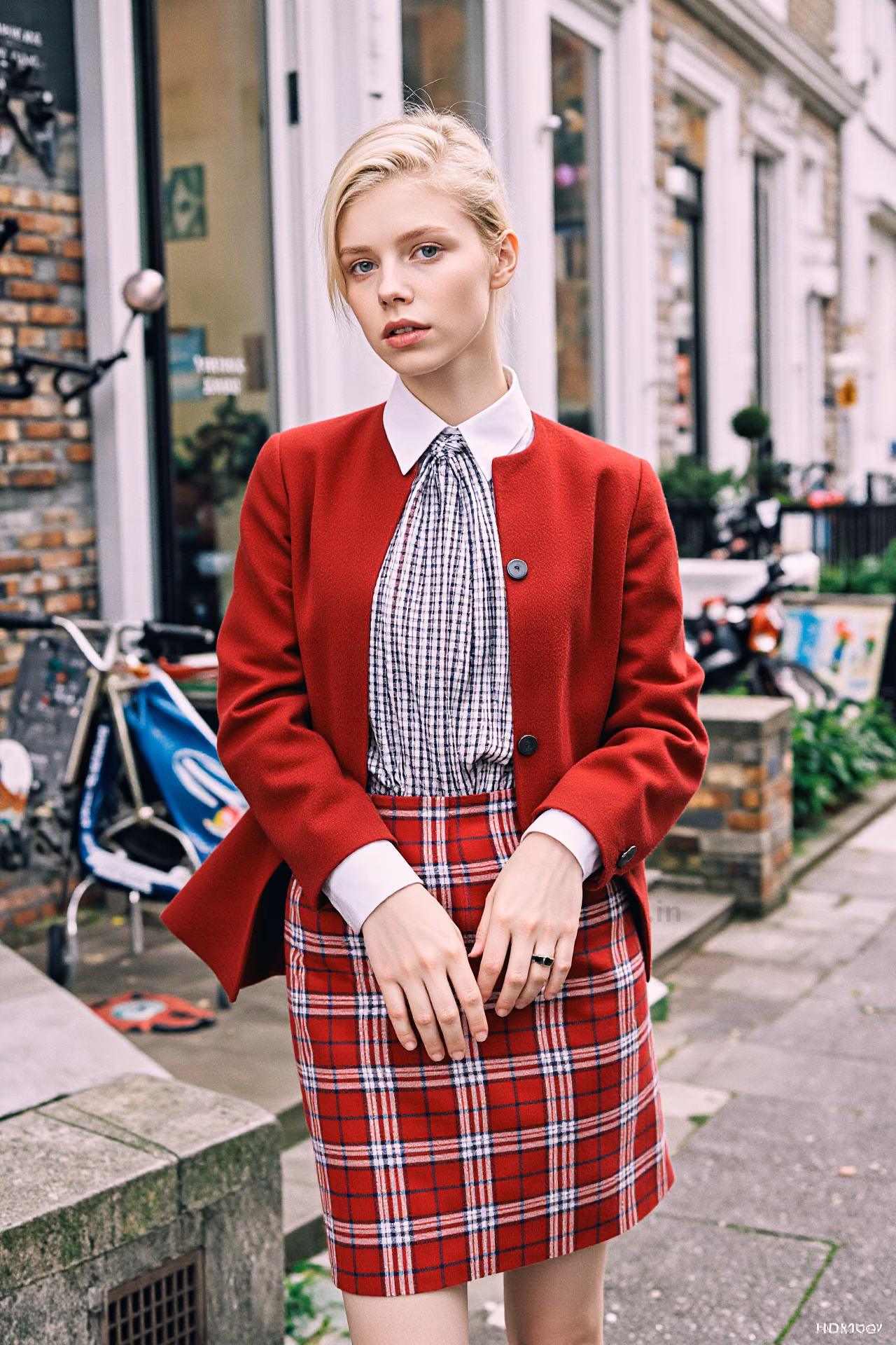 Close-up portrait of a young British woman with blonde hair and pink lips in fashionable attire, expressing love and charm.