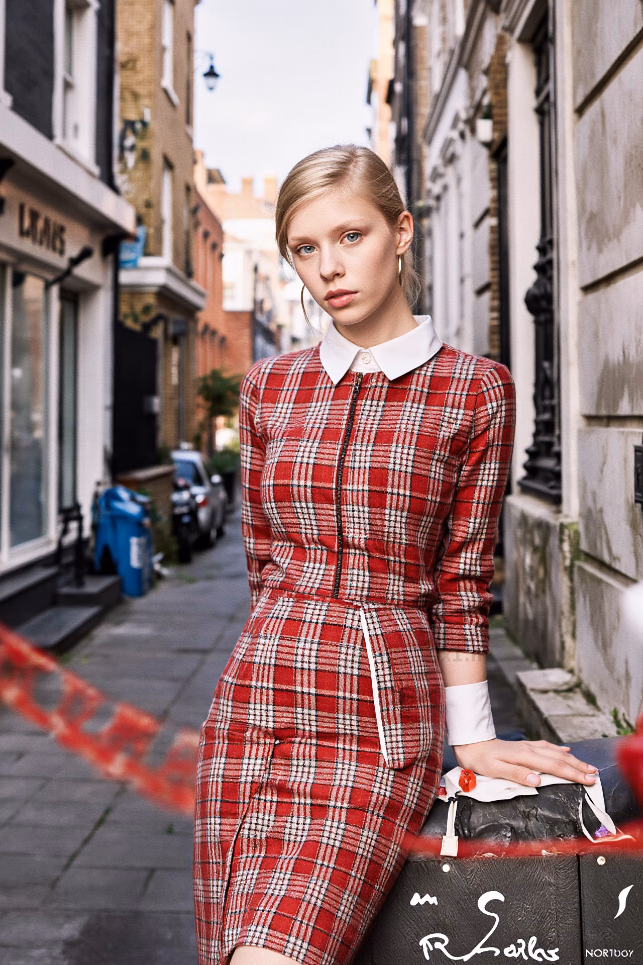 Close-up portrait of a young British woman with blonde hair and pink lips in fashionable attire, expressing love and charm.