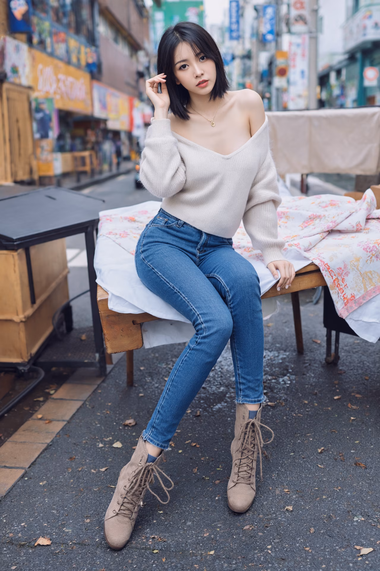 Close-up portrait of a slim Japanese woman wearing an oversized hoodie and bootcut jeans, surrounded by a Japanese street backdrop.