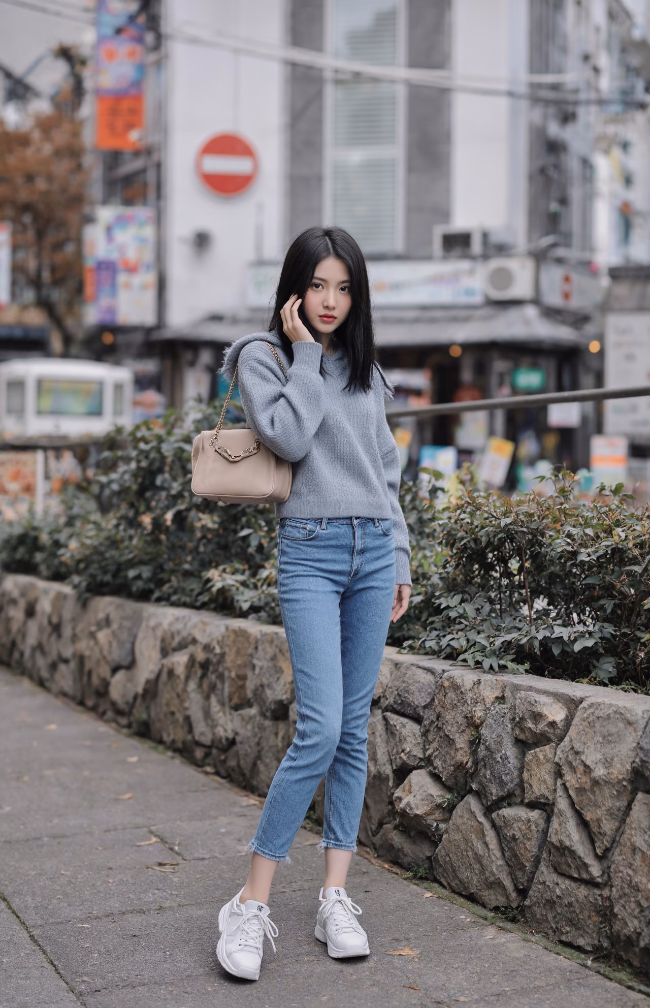 Close-up portrait of a slim Japanese woman wearing an oversized hoodie and bootcut jeans, surrounded by a Japanese street backdrop.