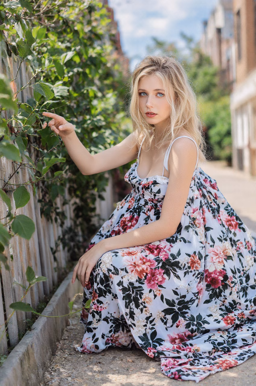 Albanian woman in a floral maxi dress, showcasing her blue eyes and ballerina bun hairstyle in various settings.