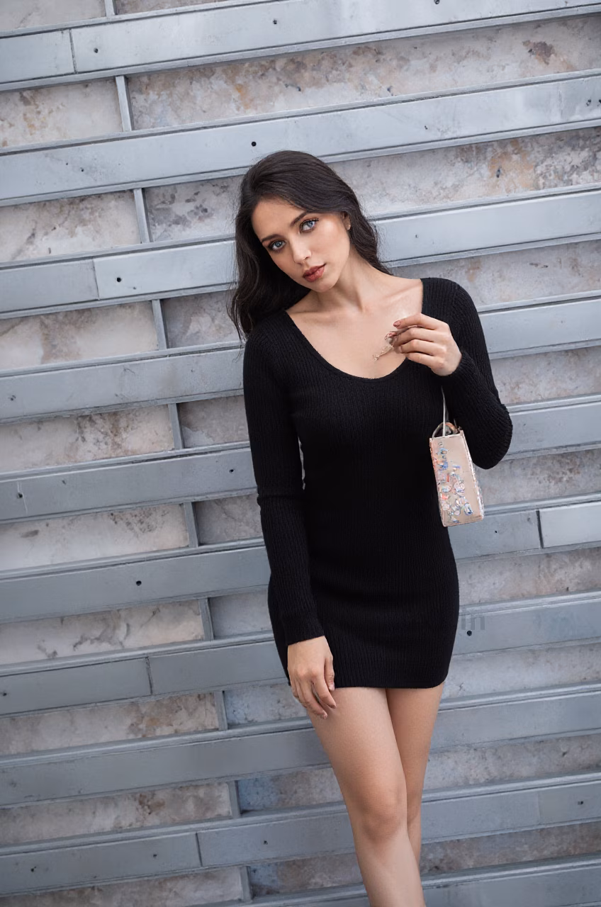 Close-up of a Croatian woman with long wavy black hair and blue eyes wearing a black bodycon mini dress, expressing love in a cozy street or living room setting.